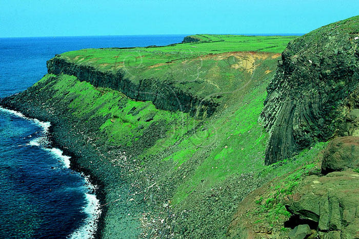 * 圖說：
				圖5.澎湖東吉島堅硬之玄武岩覆蓋於鬆散軟弱的沉積岩或凝灰岩地層上，形成平坦的方山地貌。