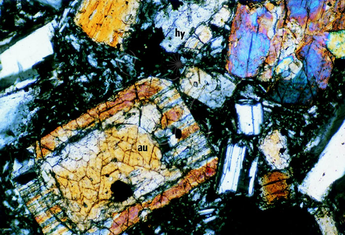 * 圖說：
				圖4.觀音山第二層斑晶稀疏的兩輝安山岩。岩石外觀上斜長石之白色斑點十分顯著。鎂驖質礦物斑晶以普通輝石(au)和紫蘇輝石(hy)為主，亦含磁鐵礦(m)。